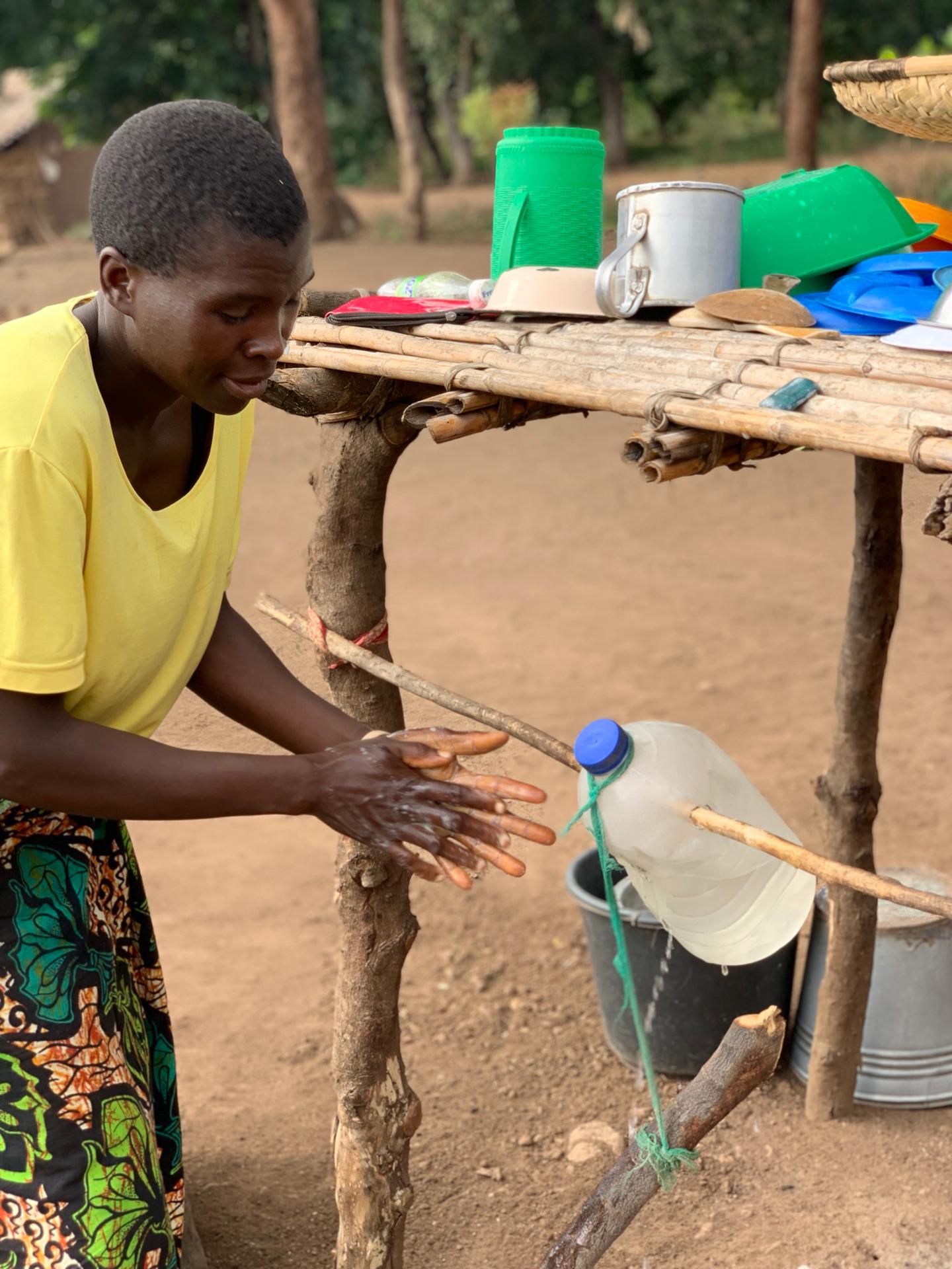 A study participant demonstrating the use of a tippy tap handwashing facility. 